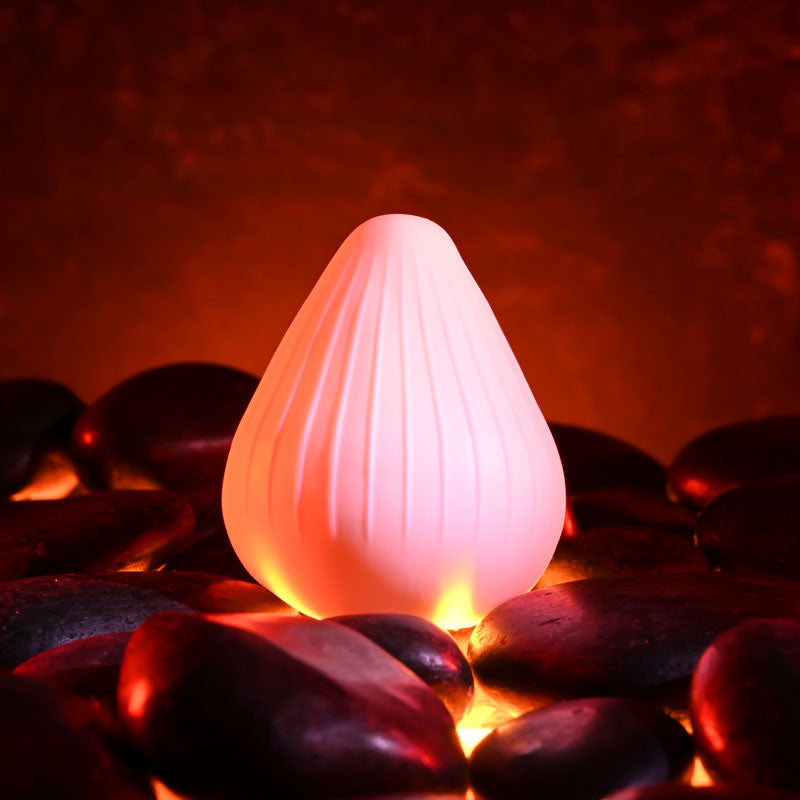 Zero Tolerance KRAKATOA -  Mini Stroker Egg on a bed of smooth stones with warm lighting.
