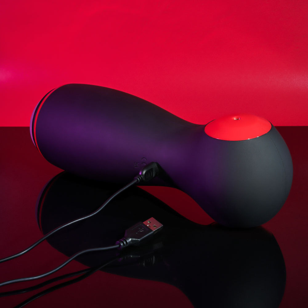 Zero Tolerance TIGHT SQUEEZE - USB Rechargeable Vibrating, Squeezing & Talking Stroker on a black surface with USB charging cable.