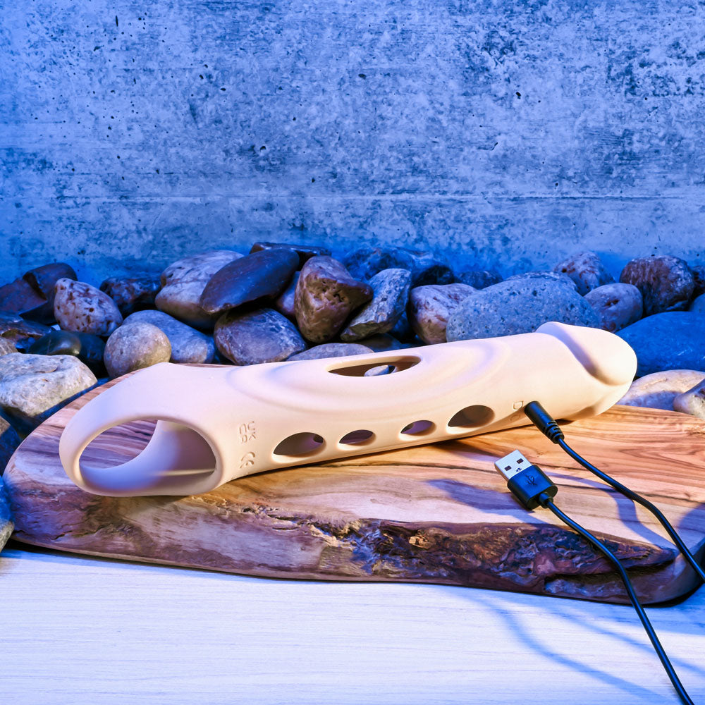Zero Tolerance BIG BOY EXTENDER - Light - USB Rechargeable Vibrating Penis Extension Sleeve on a wooden surface with stones.