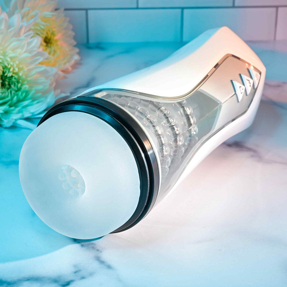 Zero Tolerance STROKING BUDDY - USB Rechargeable Vibrating & Thrusting Stroker on a marble surface with flowers.