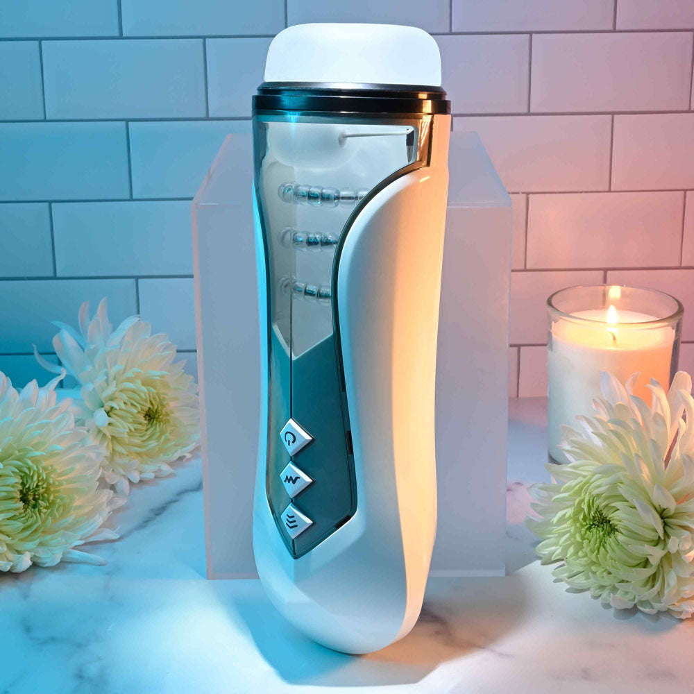 Zero Tolerance STROKING BUDDY - USB Rechargeable Vibrating & Thrusting Stroker on a marble countertop surrounded by candles and flowers.