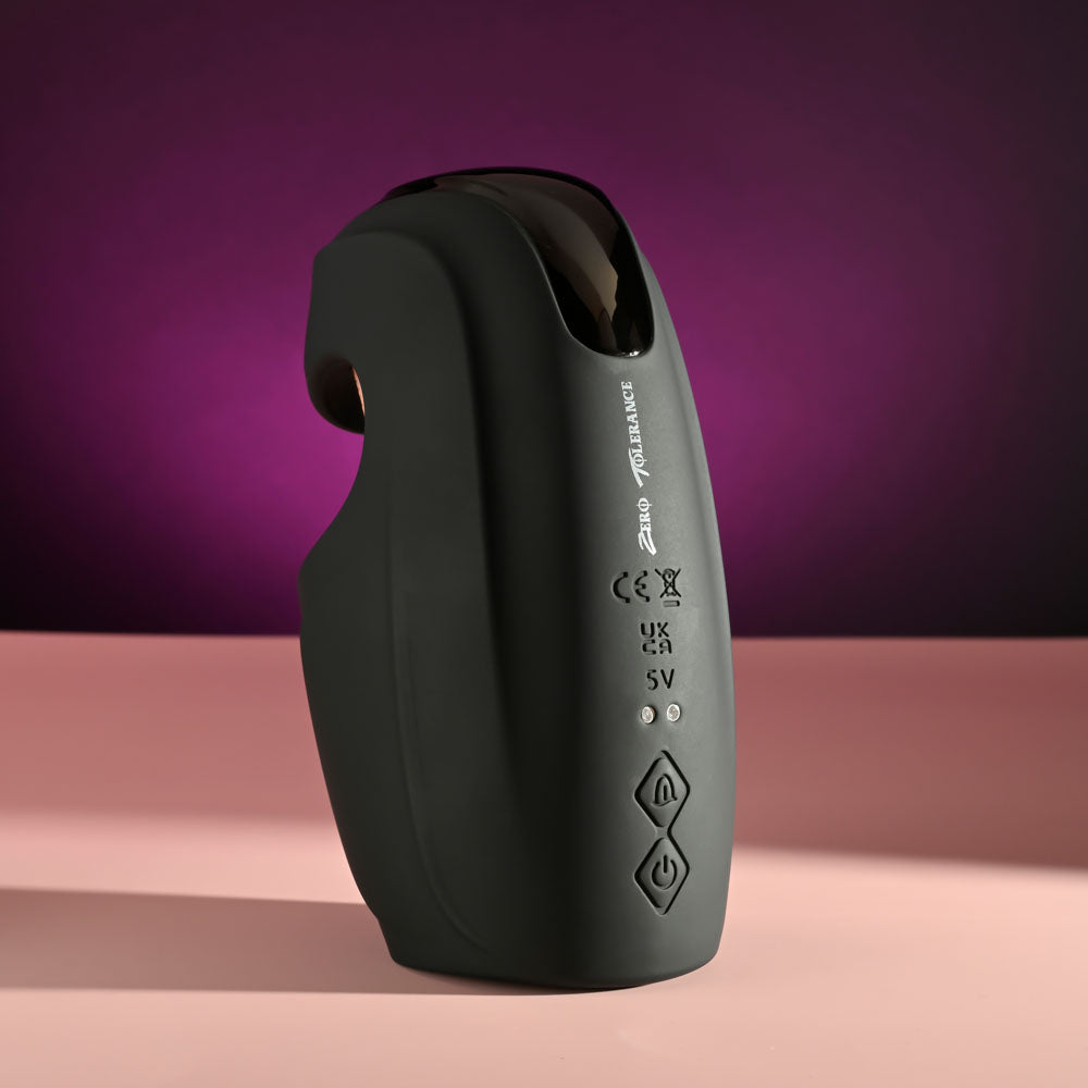 Zero Tolerance LICK THE TIP -  USB Rechargeable Vibrating & Flicking Masturbator on a pink surface with a purple background.