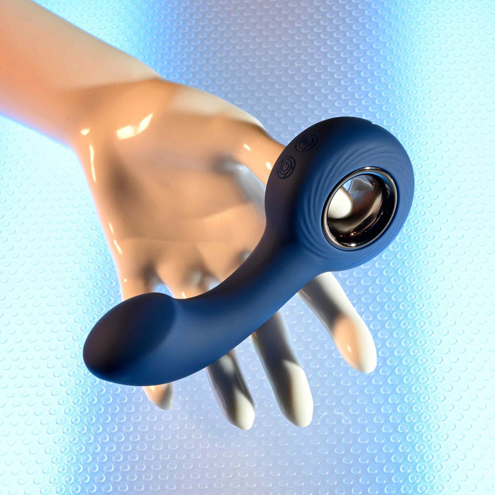 Zero Tolerance THE REACH -  13.8 cm USB Rechargeable Vibrating Anal Plug on a hand against a textured blue background.